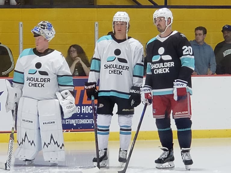 Hockey players wearing "Shoulder Check" jerseys on ice during practice