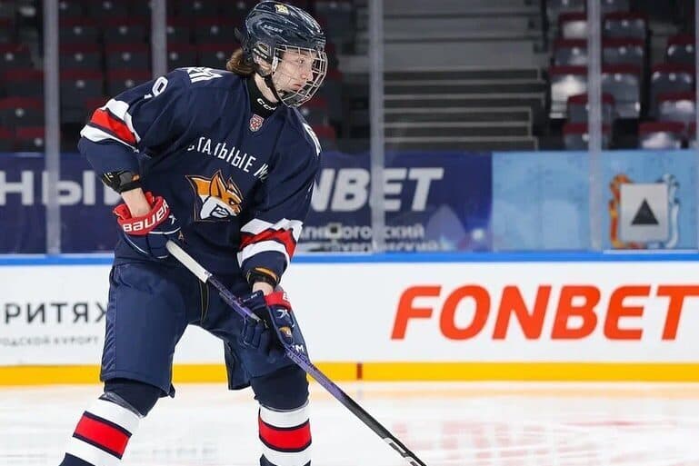 Hockey player in dark blue jersey with red and white stripes during game action