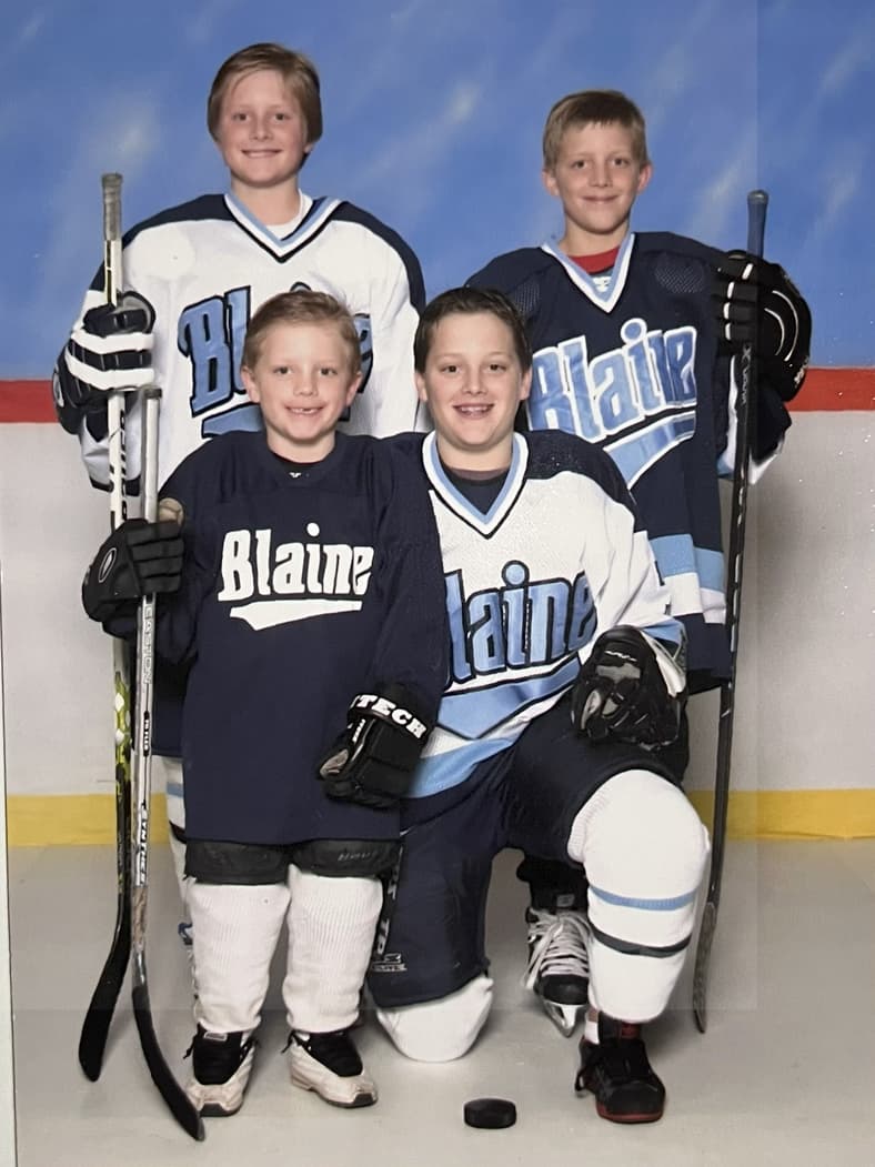 Four young hockey players in Blaine uniforms posing with sticks and equipment