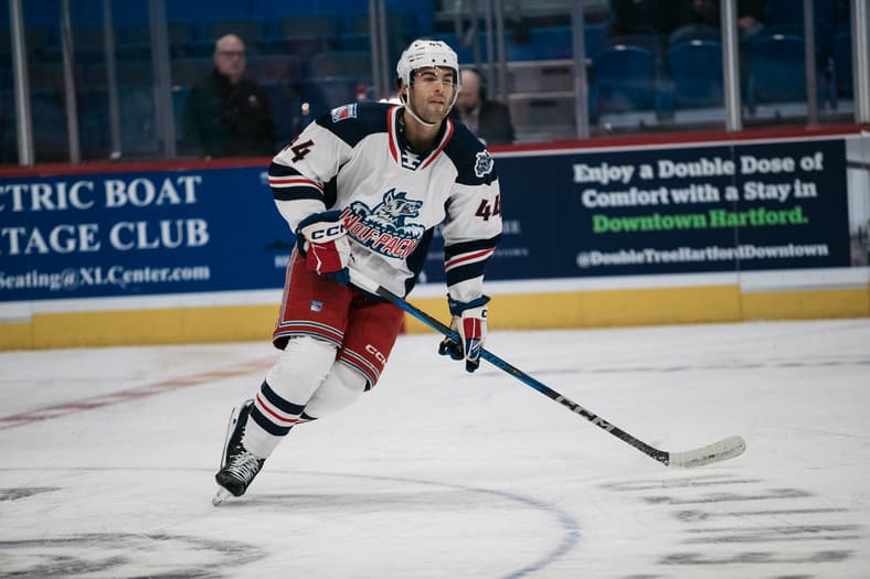 Hartford Wolf Pack player wearing #44 skating with hockey stick during game.