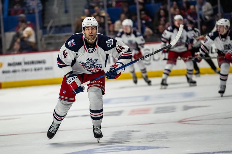 Hockey player in Rangers uniform skating with stick during game