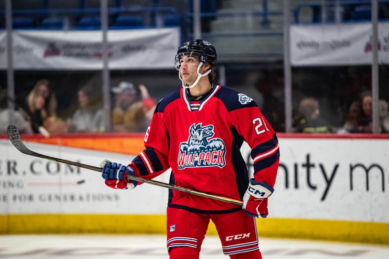 Hockey player wearing red Wolf Pack jersey number 2 during game