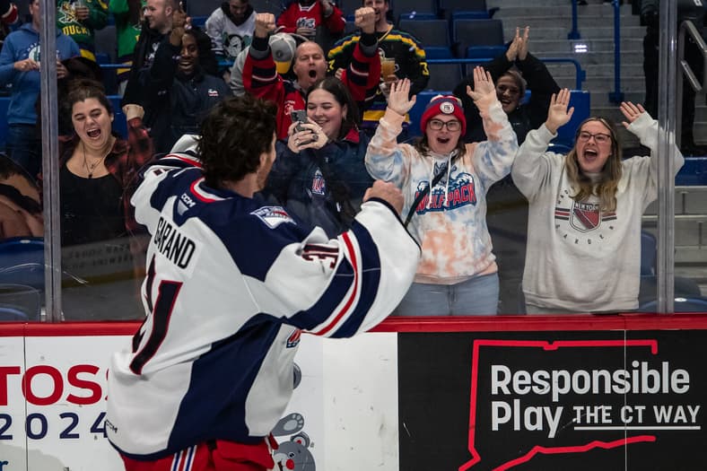 Hockey player interacting with fans at the glass during a game