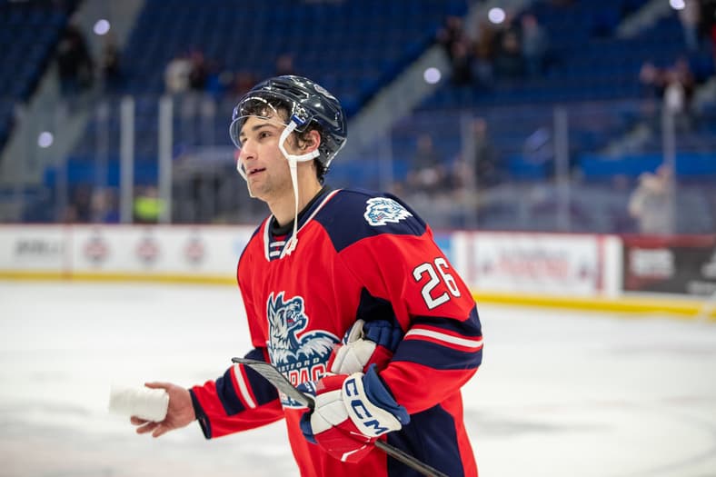 Hockey player wearing red and navy jersey number 26 during game