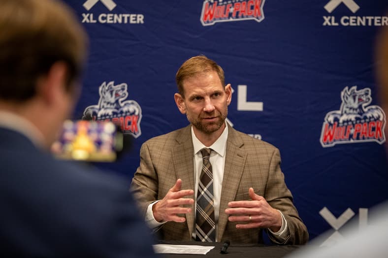 Man in tan blazer speaking at Hartford Wolf Pack press conference