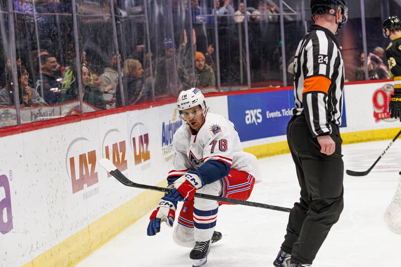 Brendan Brisson in Hartford Wolf Pack white jersey during game action with referee.
