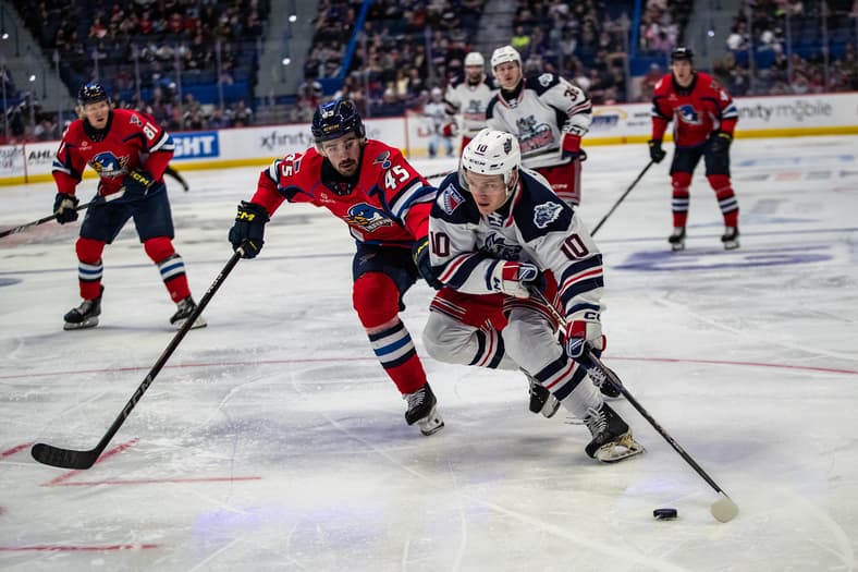 Hartford Wolf Pack player controls puck during game against opponent in red jersey