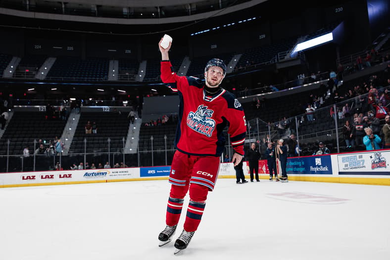 Hockey player in red jersey celebrating on ice with fist raised