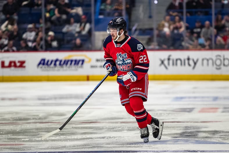 Hockey player wearing Hartford Wolf Pack red jersey number 22 skating with stick during game