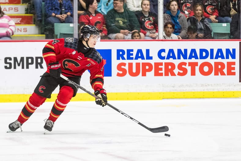 Hockey player in red and black uniform skating with puck during game