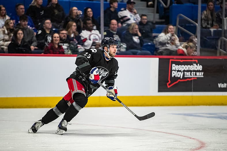 Zac Jones skating with the puck during an NHL game in his Rangers uniform