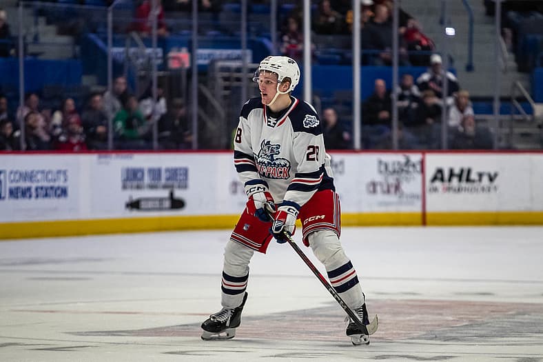 Young hockey player wearing white Rangers Attack jersey during game