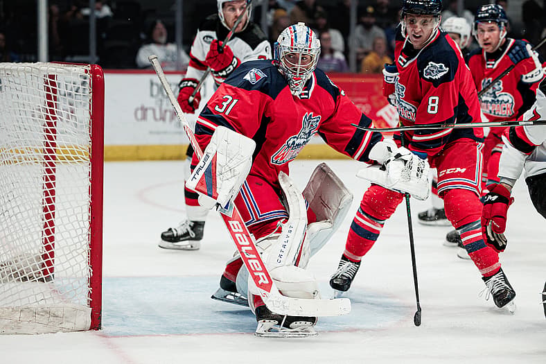 Goaltender #31 in red Hartford Wolf Pack jersey makes a save during game action