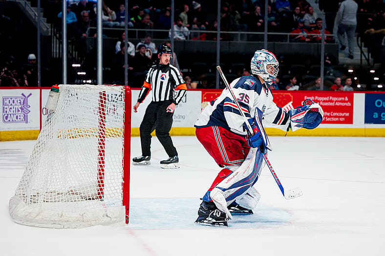 Goaltender in Rangers prospect uniform making a save during game action