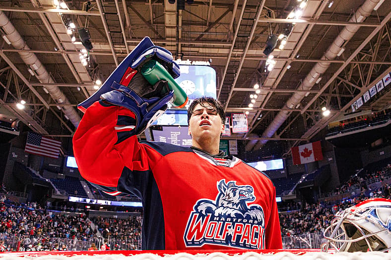 Player in Hartford Wolf Pack jersey raises gloved hand to crowd in arena