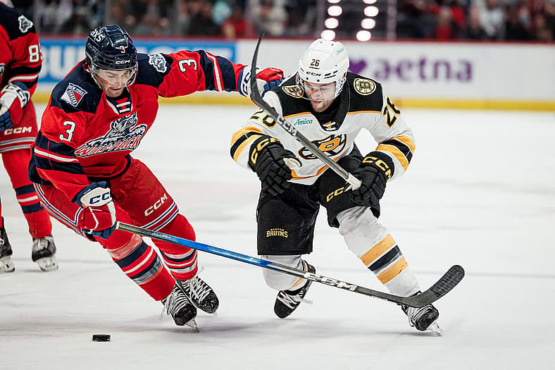 Brendan Brisson skating with puck against Hartford Wolf Pack defenseman during game