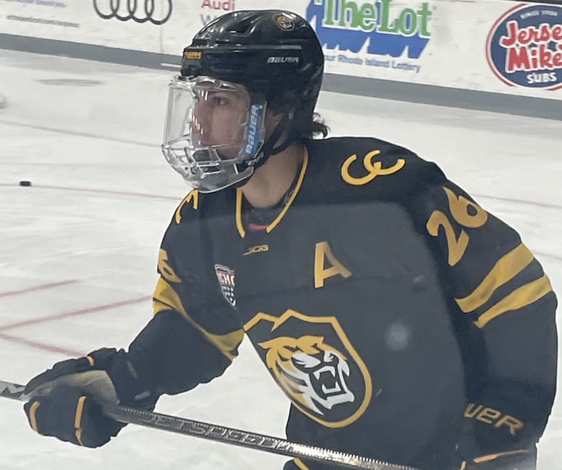 Hockey player wearing black and gold jersey with tiger logo and captain's A