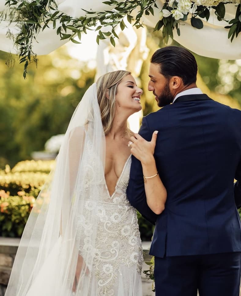 Bride and groom smiling under floral arch at wedding ceremony